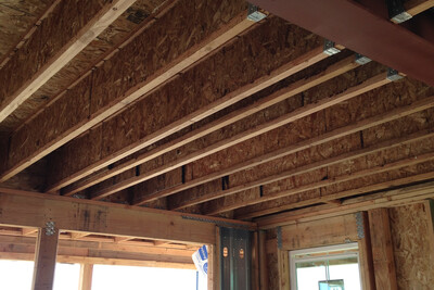 Floor framing utilizing steel wide flange beam, rim board, engineered wood I-joists and metal hangers.
