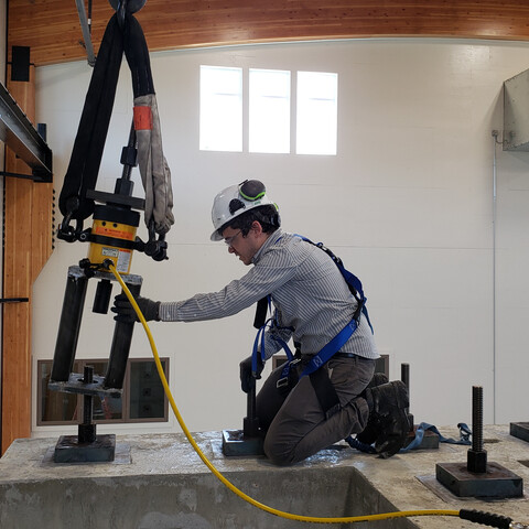 man wearing safety gear in laboratory environment kneeling on concrete